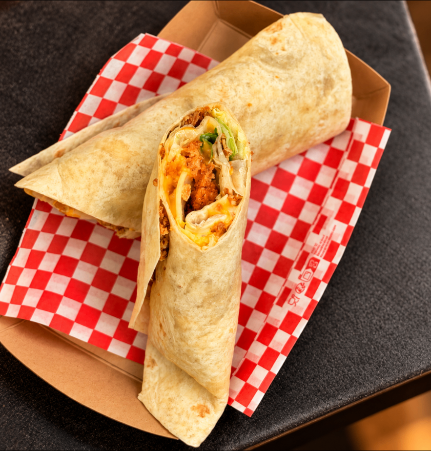 Deux wraps au poulet croustillant et cheddar fondant, coupés et présentés sur papier damier rouge et blanc